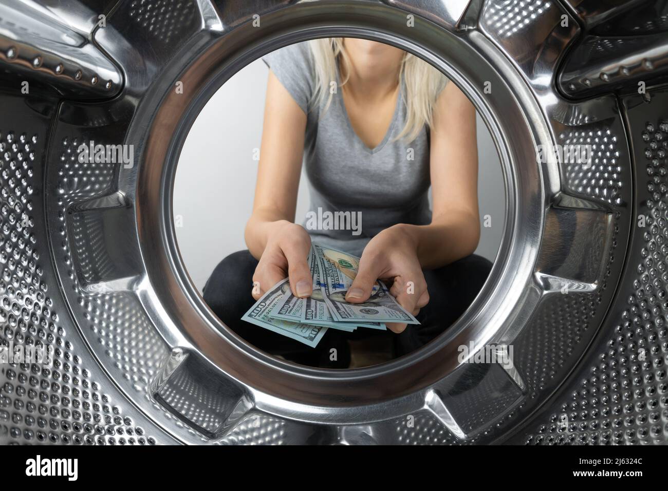 Les mains des femmes tiennent l'argent près de la machine à laver, une photo de l'intérieur du tambour de la machine à laver. Concept de paiement, blanchiment d'argent. Banque D'Images
