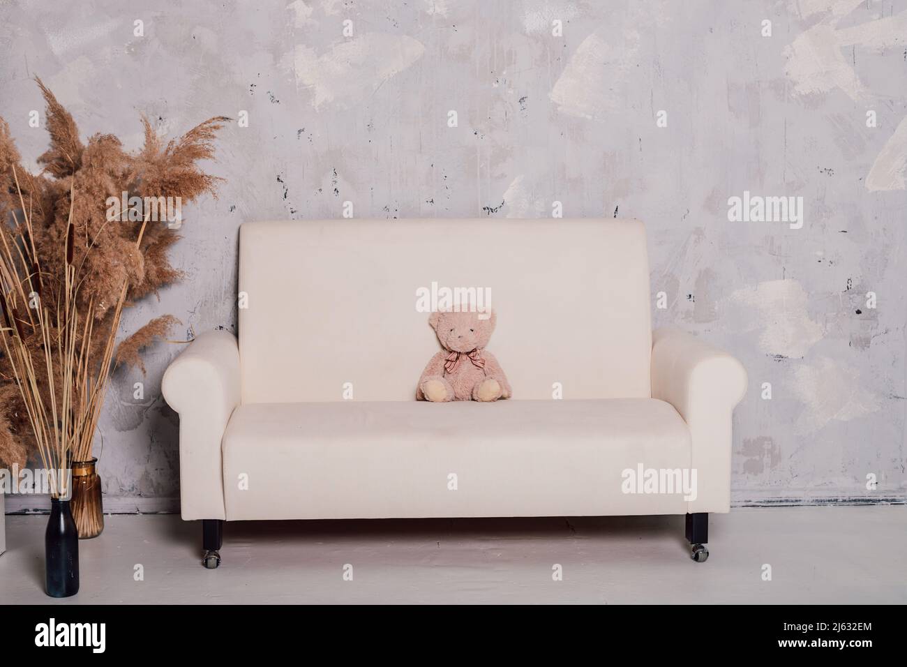 L'ours en peluche se trouve sur un magnifique canapé blanc Banque D'Images