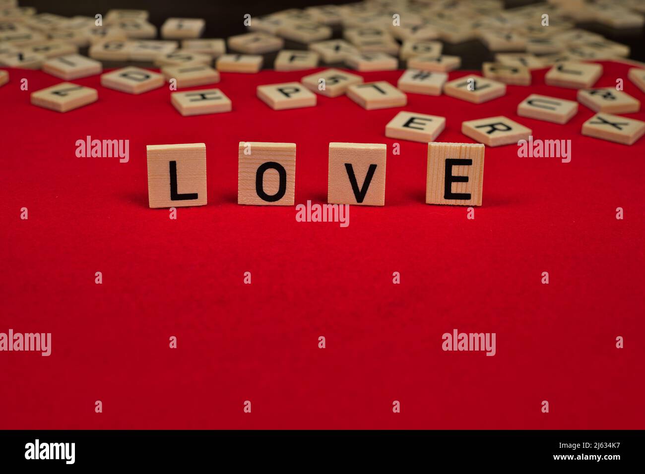 Le mot « Love » est composé d'assiettes en bois avec des lettres sur fond de feutre rouge Banque D'Images