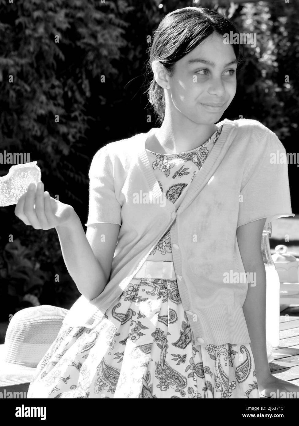 Années 1950 60's Retro style italienne fille manger toast dans le thé jardin petit déjeuner Candid. Nostalgie Banque D'Images