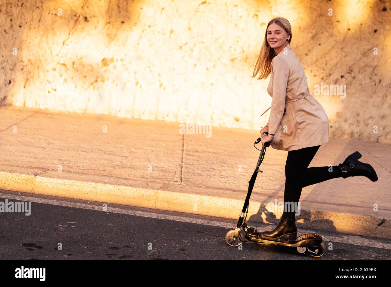 Jeune femme en train de rouler en scooter électrique. Nouveau transport urbain moderne et écologique. Écologie et concept de travail. Banque D'Images
