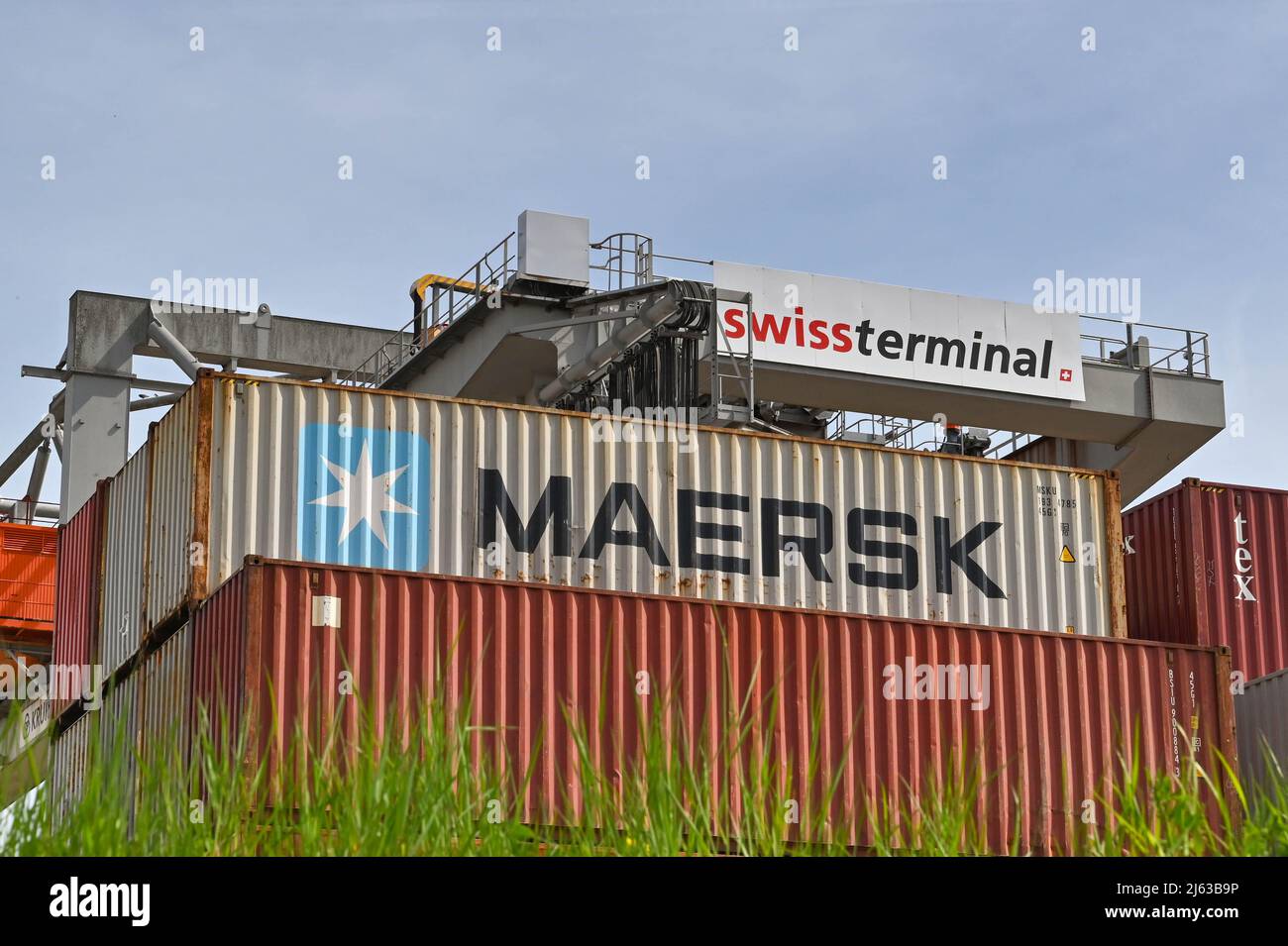 Bâle, Suisse - avril 2022 : grue lourde dans le terminal à conteneurs de la ville avec conteneurs d'expédition au premier plan Banque D'Images