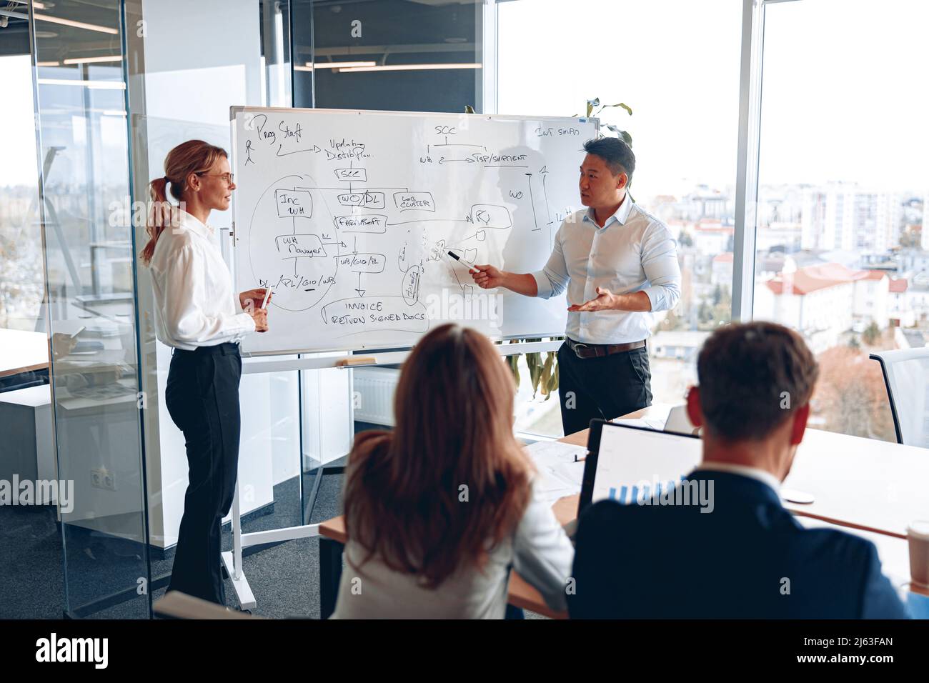 L'homme et la femme asiatiques tiennent une réunion pour les employés près d'un tableau de conférence et expliquent la stratégie de travail Banque D'Images