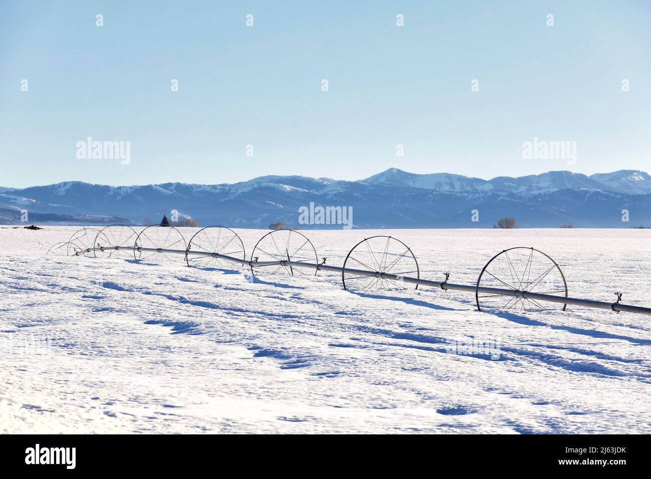 Un arroseur de ligne de roue dans un champ de ferme, en hiver avec de la neige au sol. Banque D'Images