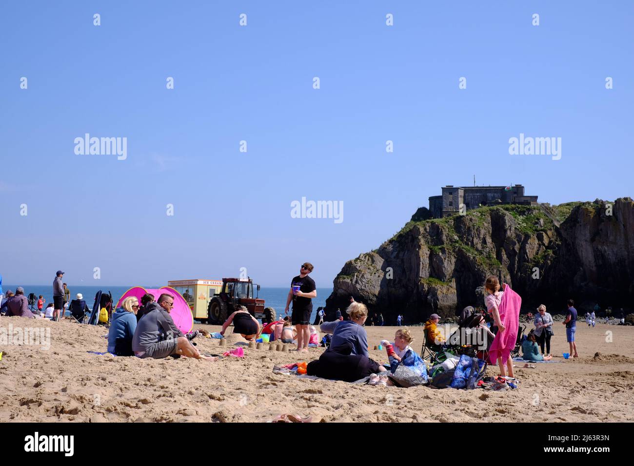 Personnes bénéficiant du soleil du début du printemps sur Castle Beach, Tenby, Pembrokeshire, pays de Galles, Royaume-Uni Banque D'Images