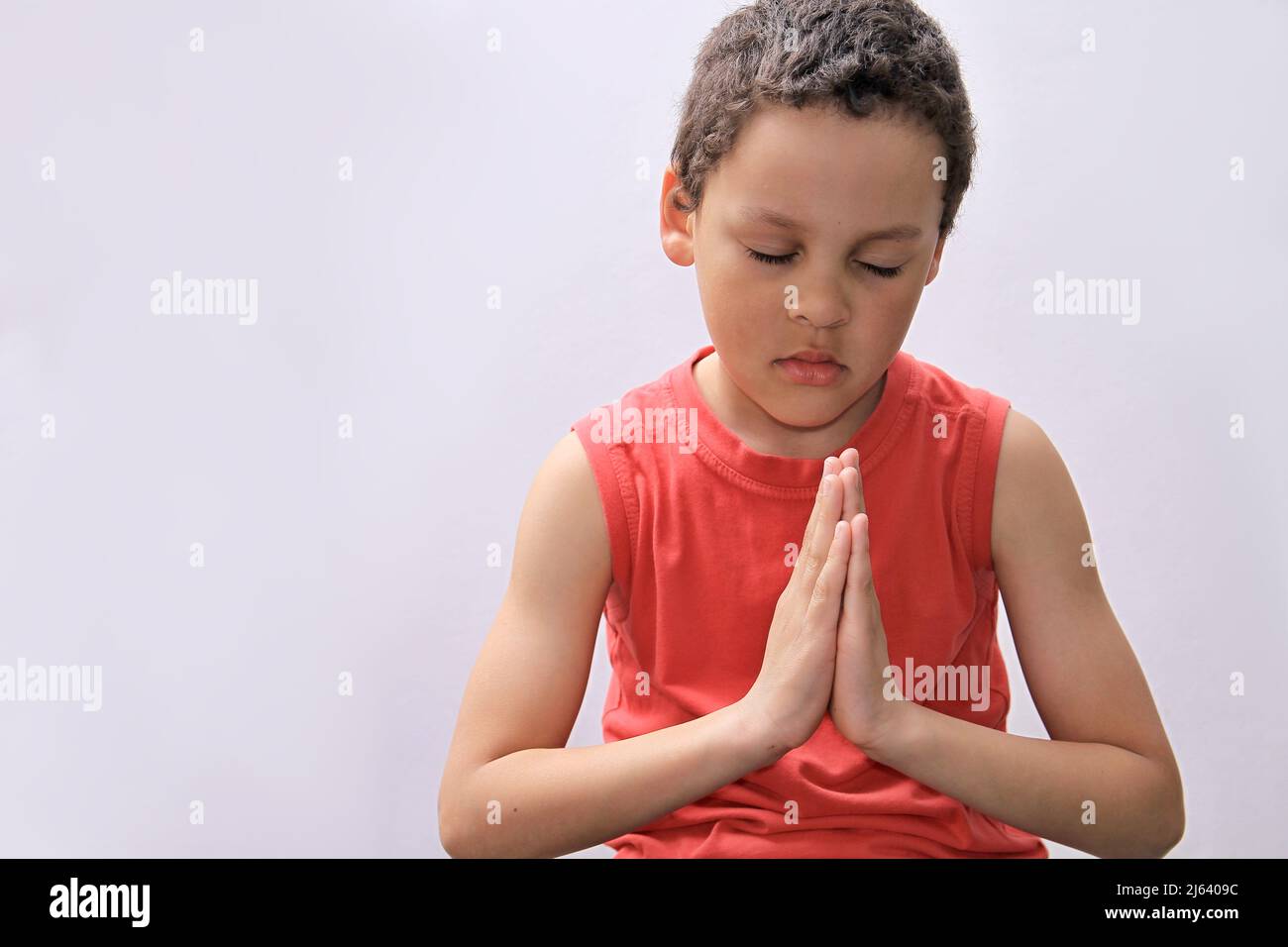 Petit garçon priant à Dieu avec les mains avec la photo de fond noire Banque D'Images