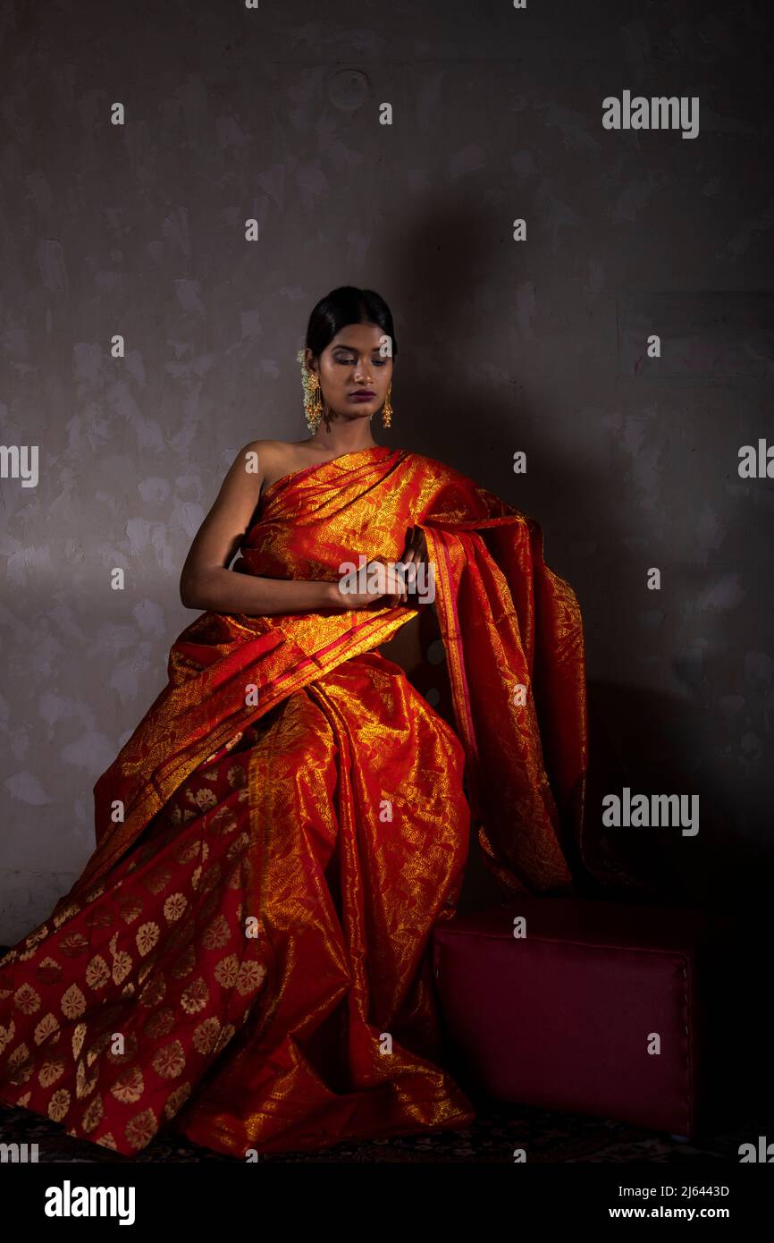 belle fille indienne portant une traditionnelle saree indienne couleur orange prise de vue dans un studio Banque D'Images