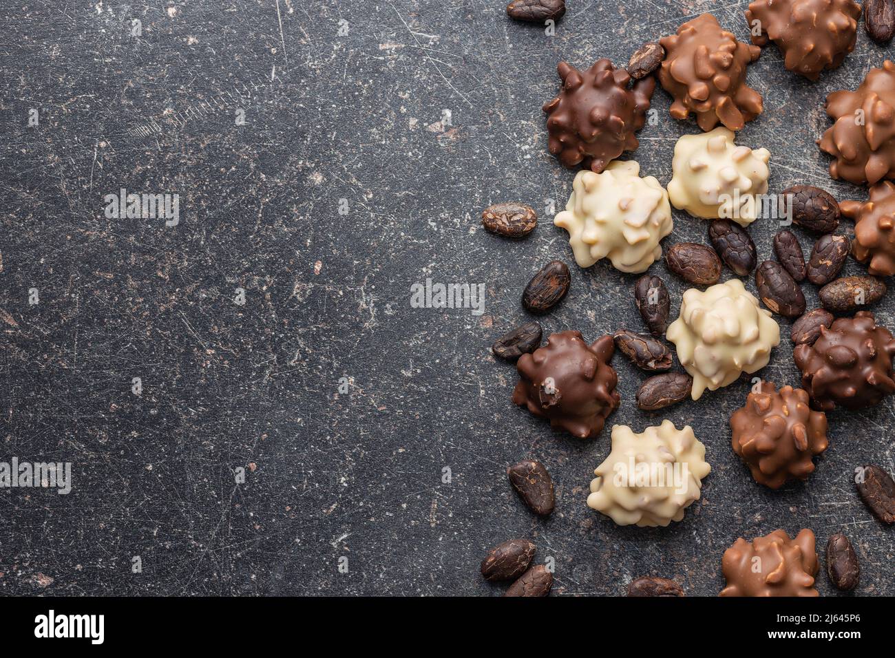 Truffes au chocolat et fèves de cacao. Pralines sucrées sur une table noire. Vue de dessus. Banque D'Images