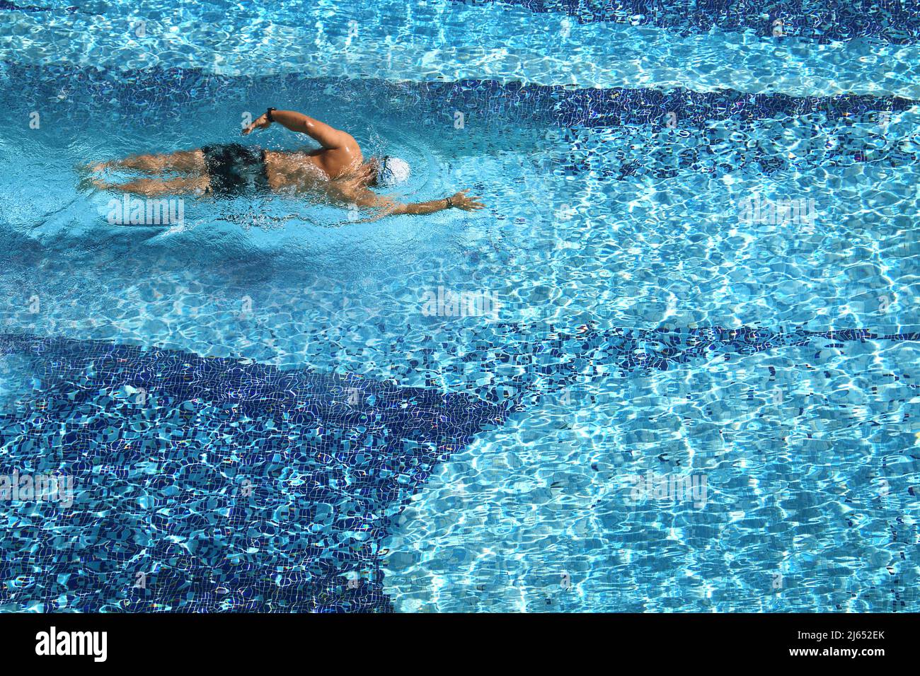 Vue aérienne d'un homme qui nage dans une piscine par beau temps. Banque D'Images