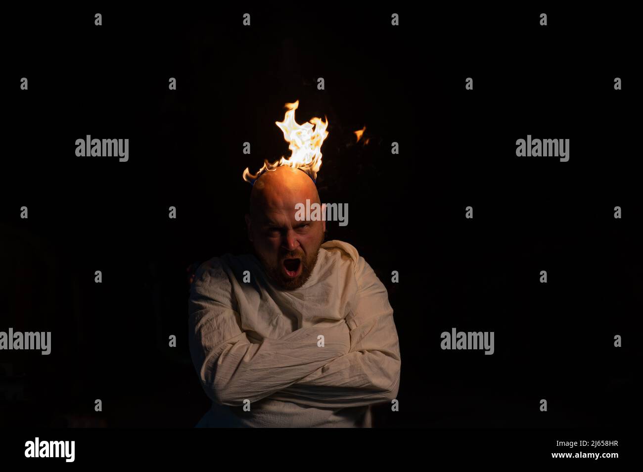 Homme chauve dans un blouson avec une tête brûlante sur un fond sombre. Banque D'Images