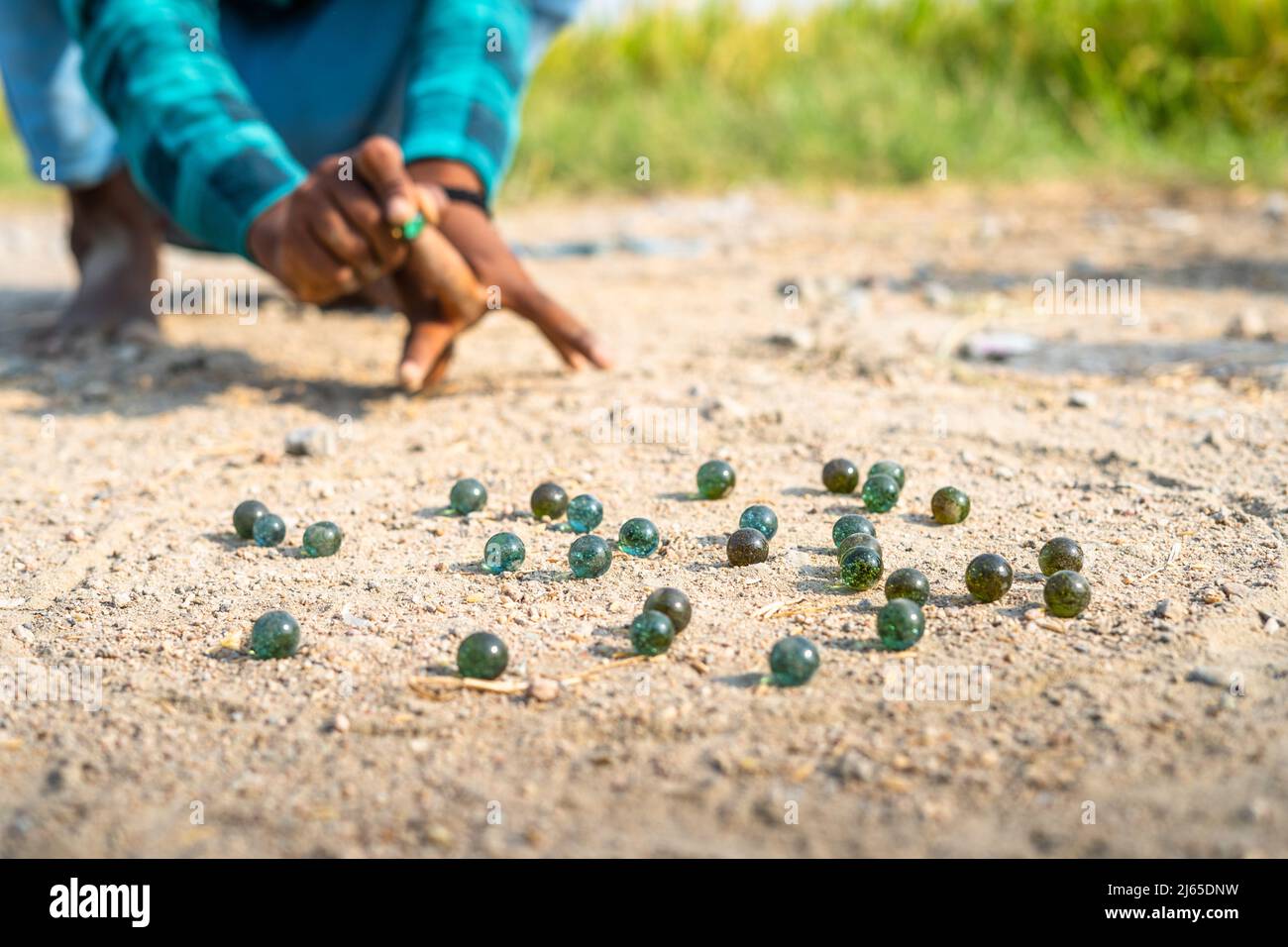 Gros plan de pleurs d'enfants en frappant des goli ou des billes de verre sur le bord de la route au village indien - concat de sports de village, l'Inde rurale et de loisirs Banque D'Images