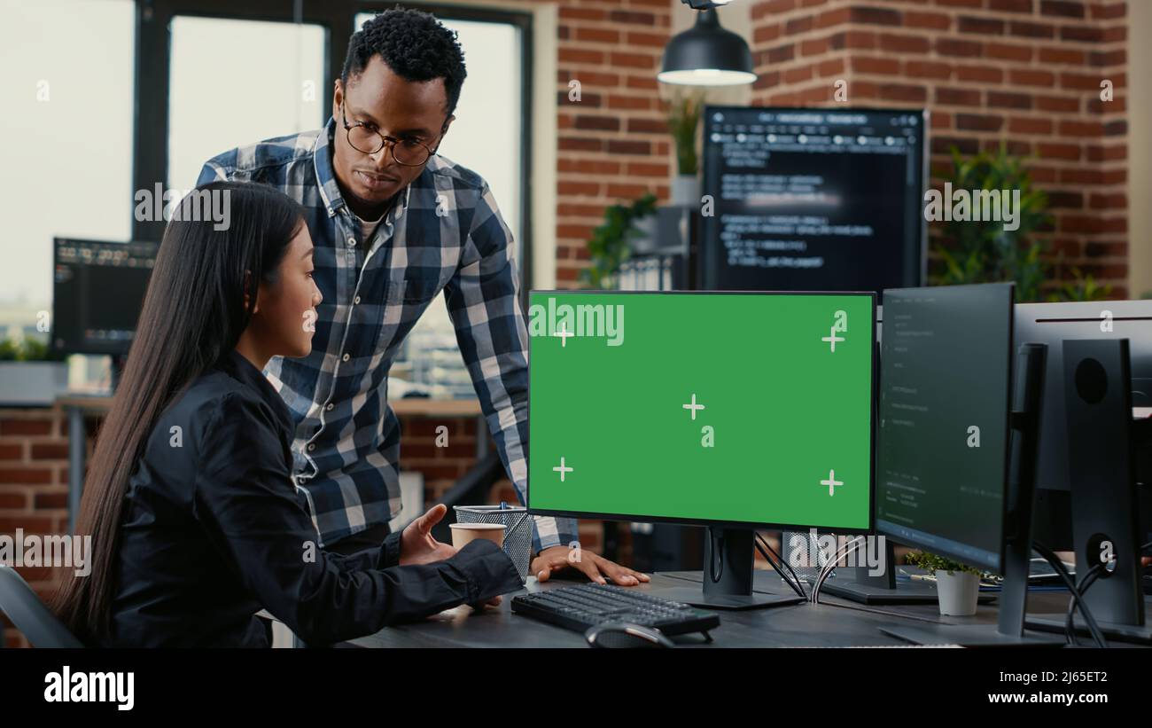 Équipe mixte de programmeurs analysant le code source regardant l'écran vert chroma key mockup discutant de l'algorithme. Développeurs d'applications travaillant sur le cloud computing en ligne dans la salle des serveurs. Banque D'Images