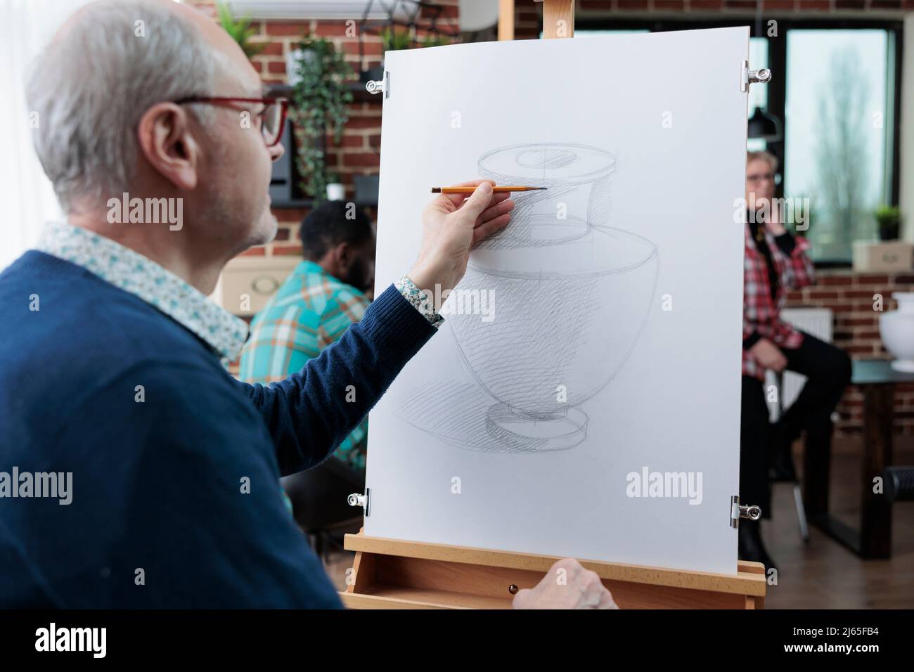 Modèle de vase de dessin étudiant âgé sur toile blanche utilisant la technique d'esquisse pendant la classe d'art en studio de créativité. Équipe diversifiée participant à une leçon créative développant les compétences artistiques Banque D'Images