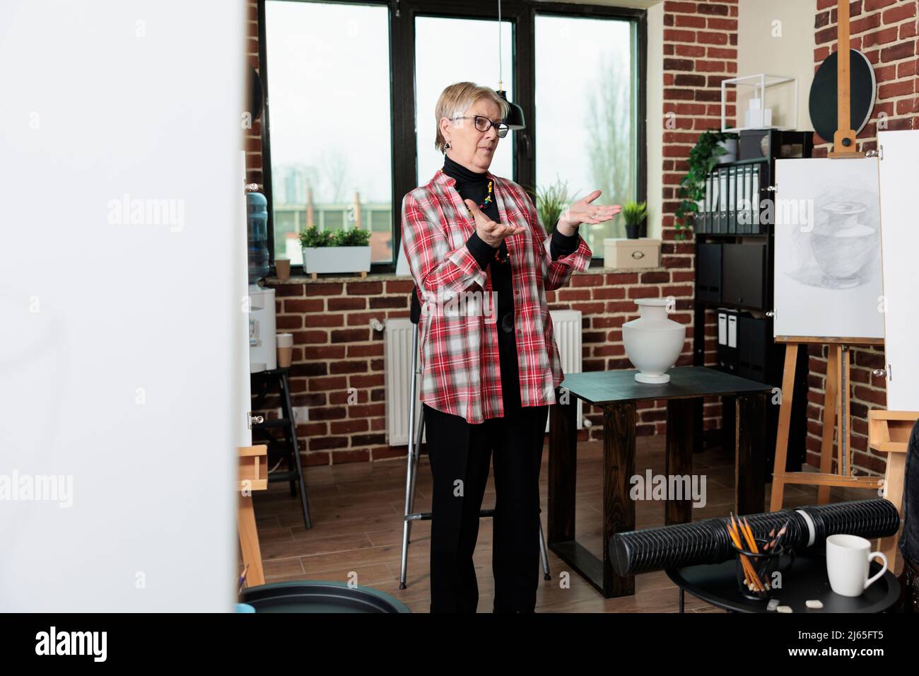 Professeur aîné expliquant la technique d'esquisse à des étudiants multiethniques d'art pendant l'atelier de création. Diverses équipes apprennent à dessiner un modèle sur toile à l'aide d'un crayon graphique. Résolutions du nouvel an Banque D'Images