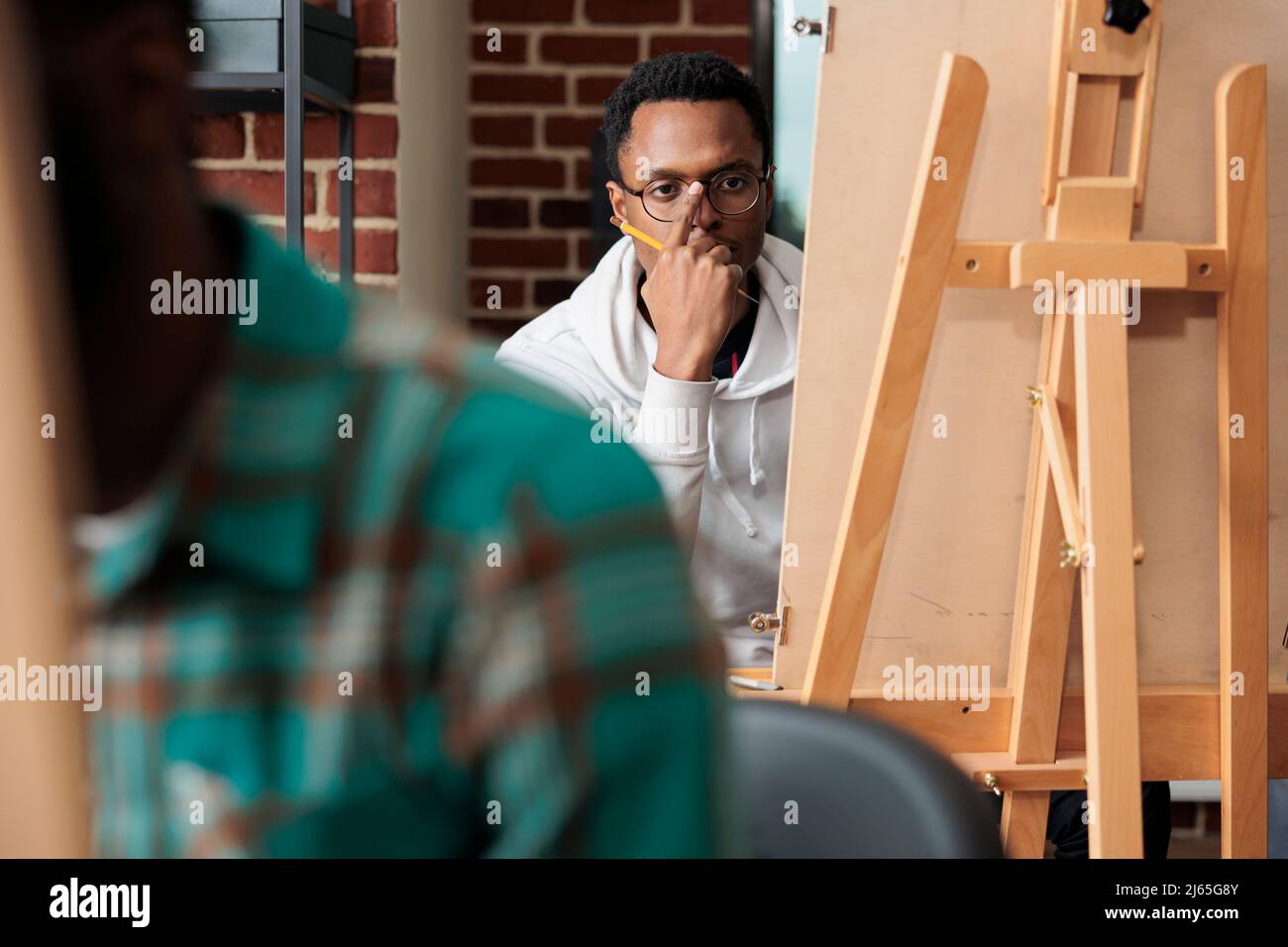 Portrait d'un jeune artiste homme regardant un vase esquissant un modèle à l'aide d'un crayon graphique à dessin. Équipe d'étudiants créatifs apprenant la technique d'esquisse de création d'œuvres d'art modernes sur toile. Résolutions du nouvel an Banque D'Images