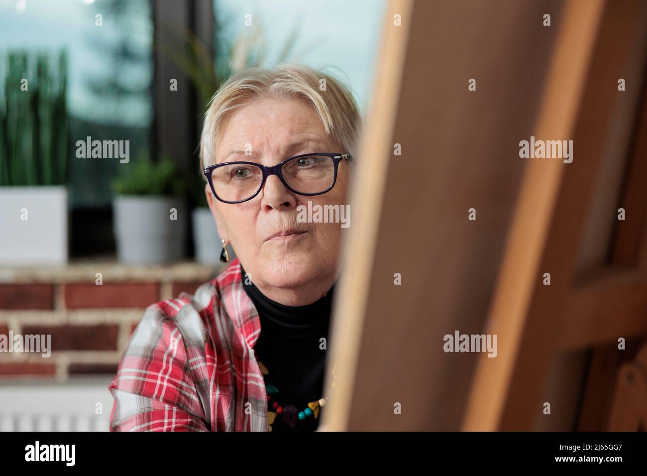 Portrait d'un professeur de peintre aîné dessinant un croquis sur toile graphique pendant les cours d'art dans un lieu de travail mural en brique. Groupe de personnes apprenant à dessiner à l'aide de la technique d'illustration. Résolutions du nouvel an Banque D'Images