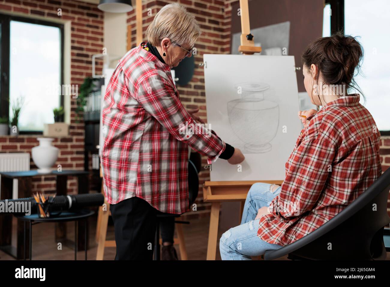 Professeur d'art âgé montrant la technique d'esquisse au jeune artiste pendant la leçon de créativité en studio scolaire. Artiste peintre étudiant dessin vase croquis à l'aide de crayon graphique travaillant à la croissance personnelle Banque D'Images