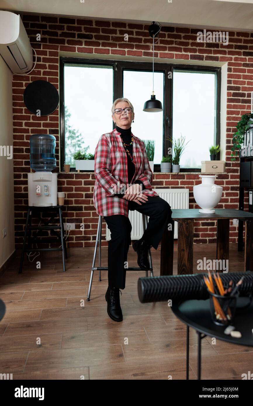 Portrait d'un professeur d'artiste âgé debout sur une chaise dans un studio de créativité pendant la classe d'art. Peintre senior enseignant la technique graphique aux étudiants travaillant à l'art créatif. Résolutions du nouvel an Banque D'Images
