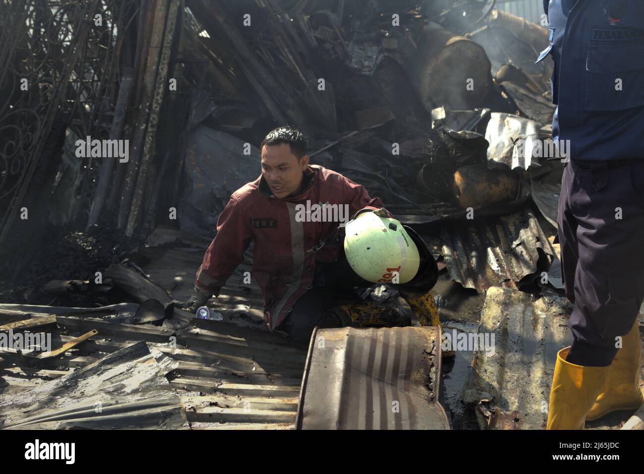 Un pompier épuisé reposant entre les débris après un accident d'incendie a brûlé des bâtiments d'entreposage d'une industrie domestique à Kebayoran Lama, dans le sud de Jakarta, Jakarta, Indonésie. Banque D'Images