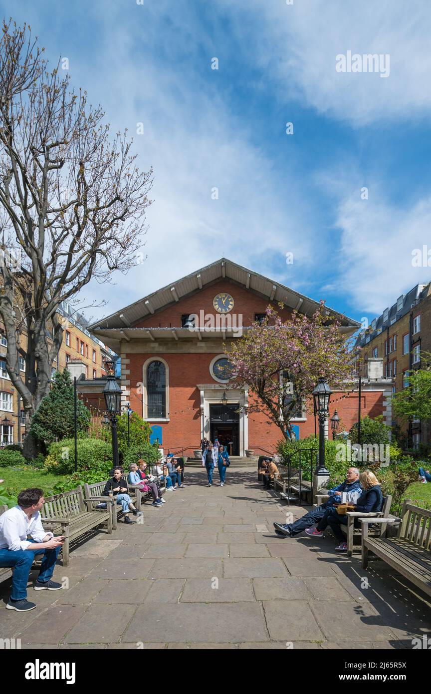 Les gens assis sur des bancs socialisent et se détendent dans le jardin de l'église St Paul à Covent Garden lors d'une journée ensoleillée de printemps. Londres, Angleterre, Royaume-Uni. Banque D'Images