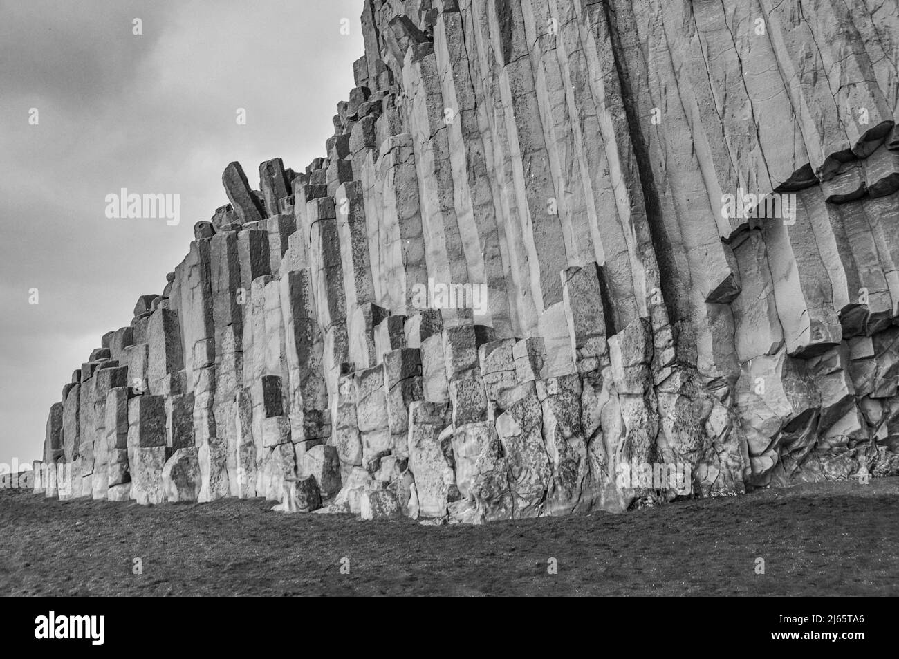 Schwarzweißaufnahme der Basaltsäulen am Reynisfjara-Strand, rechts die Höhle Reynishellir (Südisland) - photo en noir et blanc des colonnes de basalte en Islande Banque D'Images