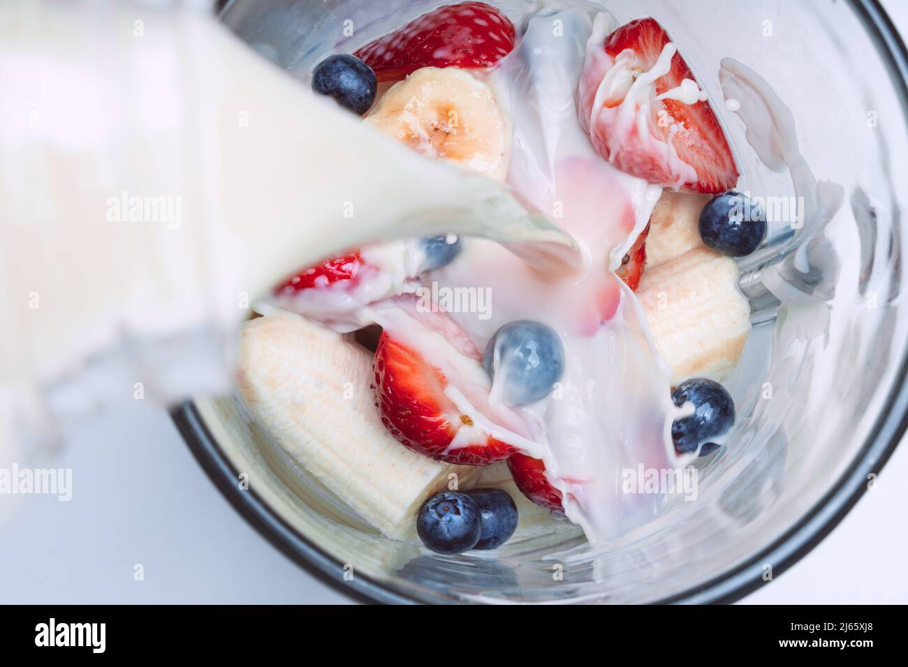 Préparer du smoothie ou du milkshake dans le blender. Verser du lait dans un blender avec des fruits. Smoothie végétalien au lait d'amande Banque D'Images