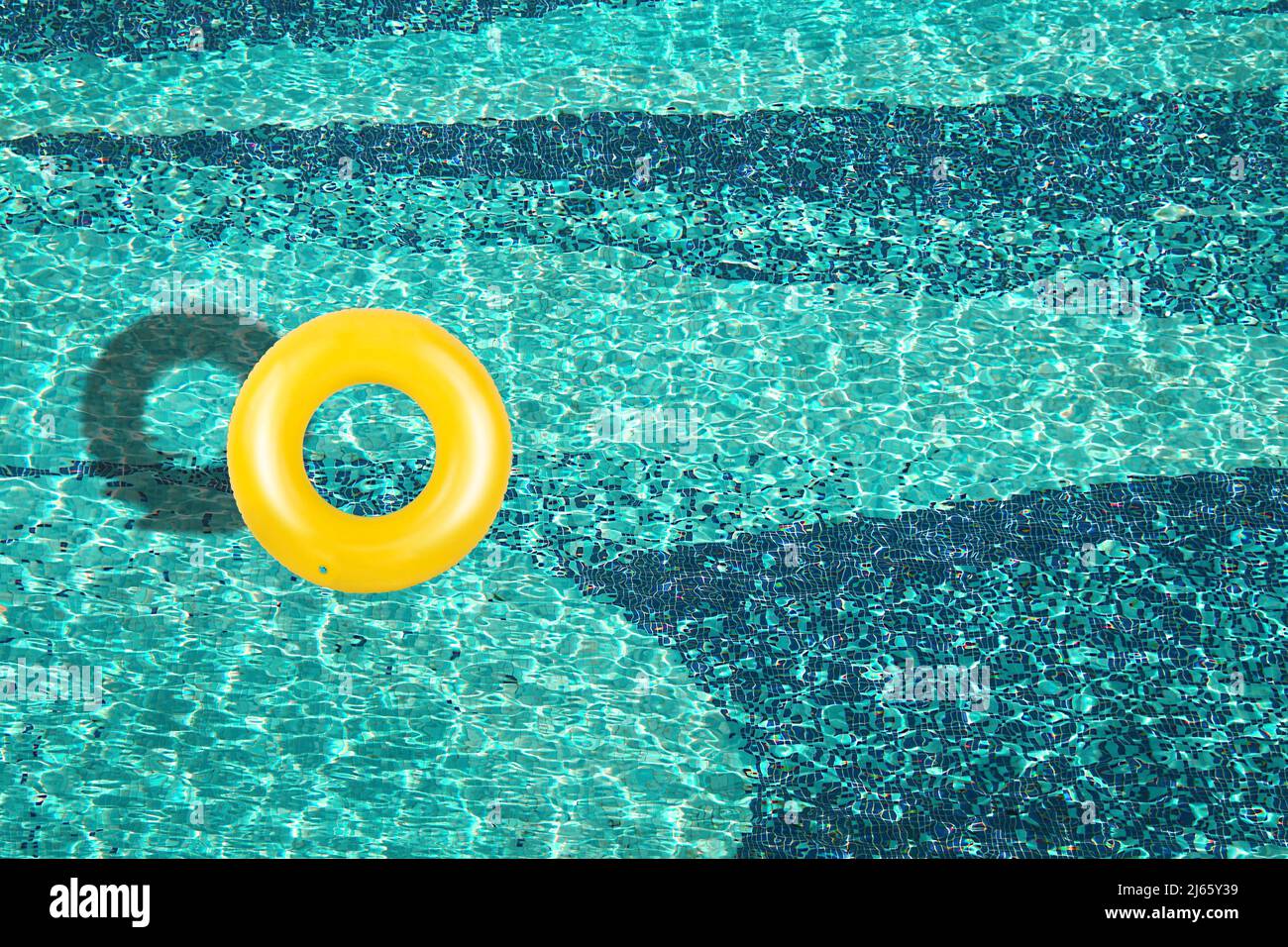 Vue aérienne de l'anneau jaune flottant dans une piscine bleue sous une journée ensoleillée Banque D'Images