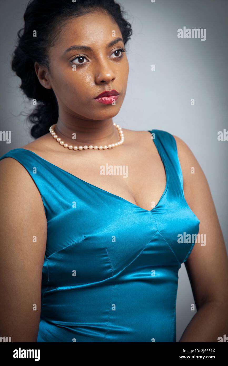 Femme avec perles en robe bleue satinée Banque D'Images
