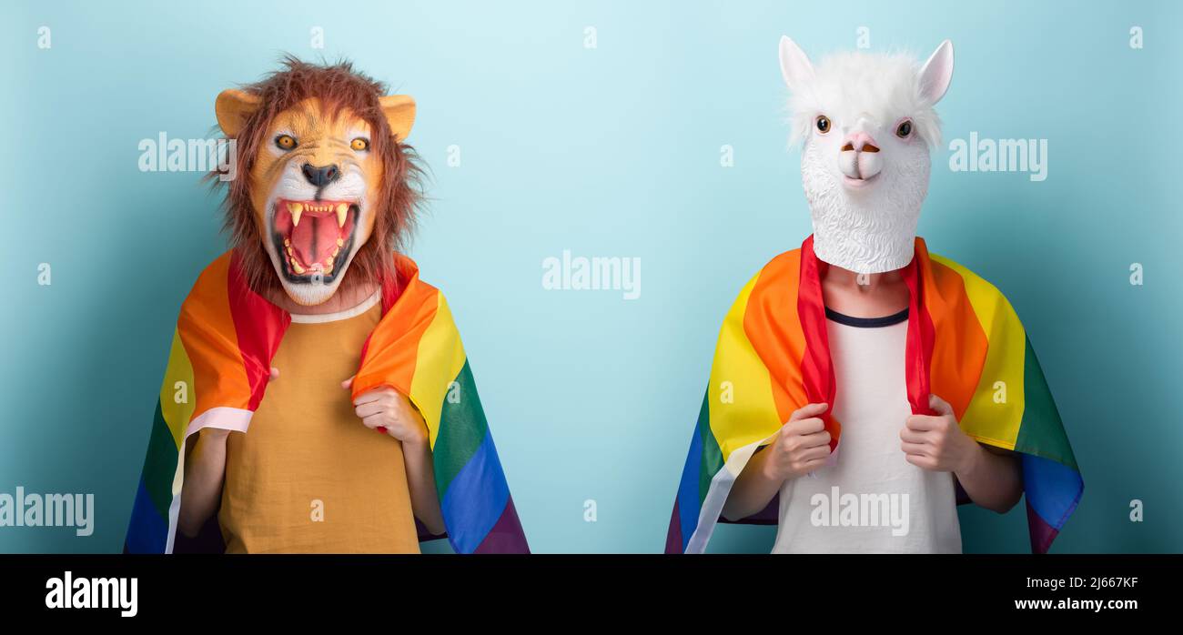 La jeune femme en lion et masque alpaga porte un drapeau de fierté lgbt arc-en-ciel enveloppé autour des épaules, isolé sur fond bleu Banque D'Images