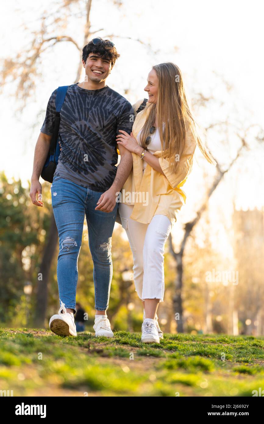 Jeune couple hétérosexuel marchant dans un parc et parlant Banque D'Images