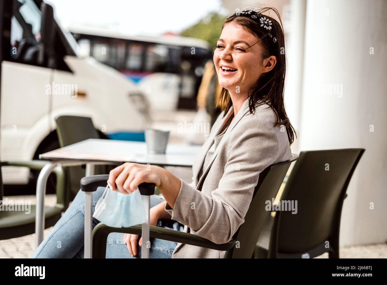 Un jeune voyageur avec ses bagages et son masque de protection assis dans le café et attendant que son bus vienne Banque D'Images