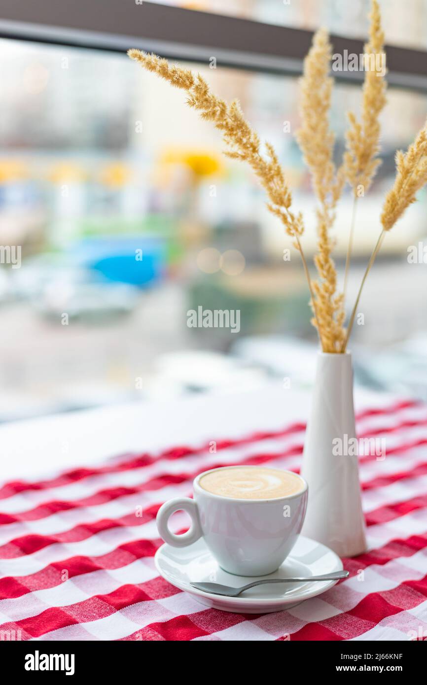 Une tasse de cappuccino se tient sur la table dans un café dans un intérieur lumineux Banque D'Images