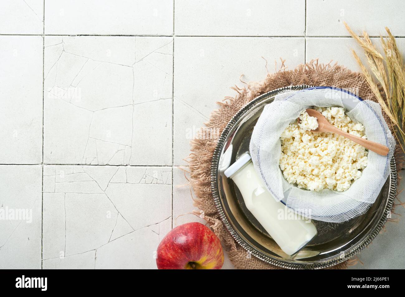 Fête juive de Shavuot. Lait et fromage, blé mûr et fruits, crème vieux panneau fissuré mur fond. Produits laitiers sur bois blanc b Banque D'Images