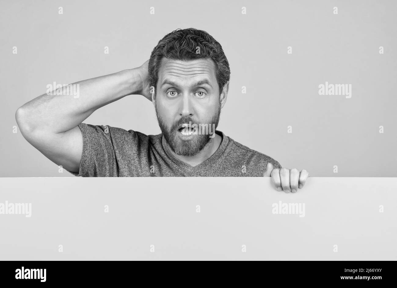 un homme mûr choqué avec un visage surpris derrière le papier jaune pour l'espace de copie, surprise Banque D'Images