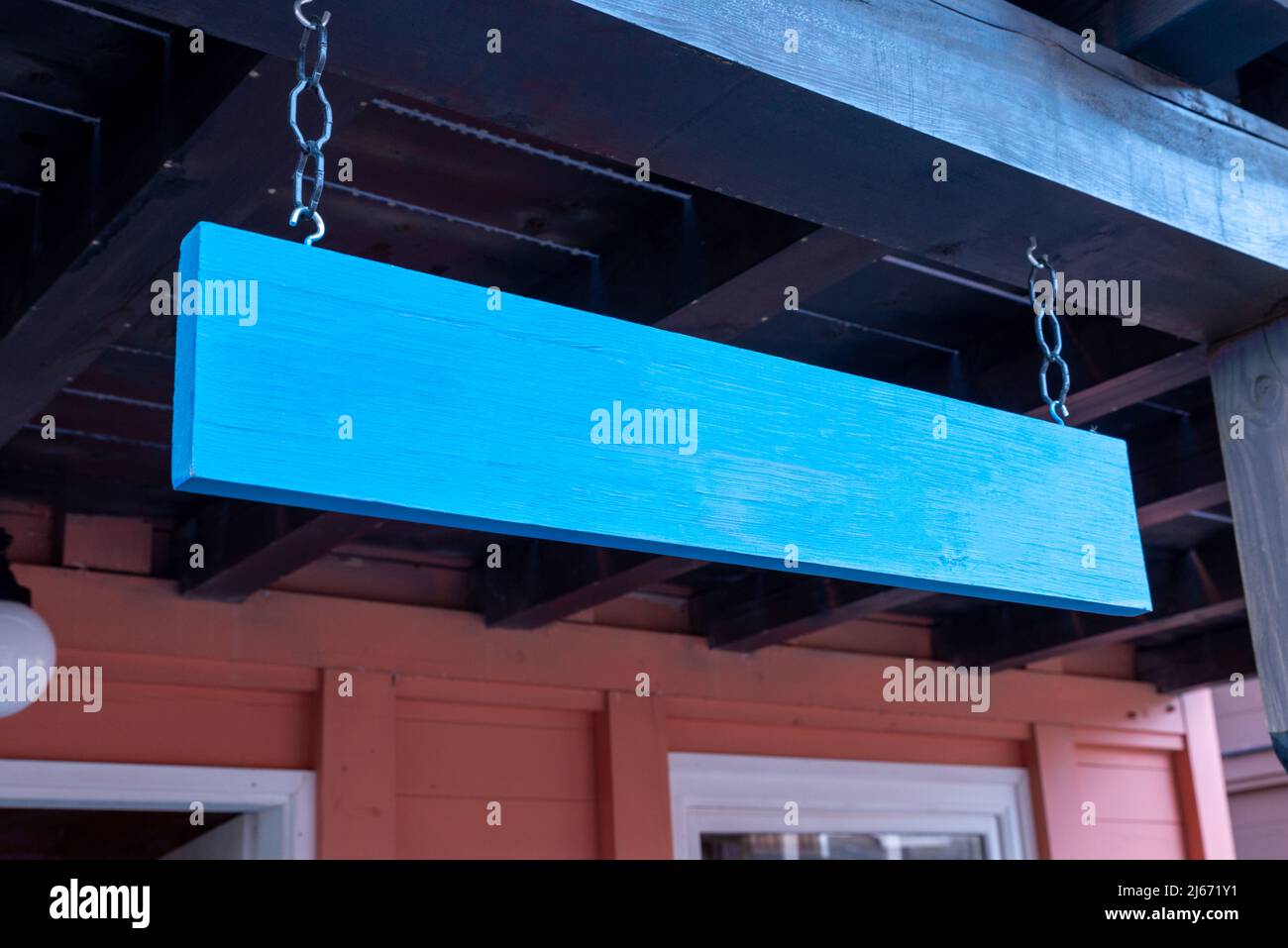 Panneau en bois bleu suspendu à l'entrée du magasin. Nettoyer la surface pour la présentation du logo ou du nom Banque D'Images