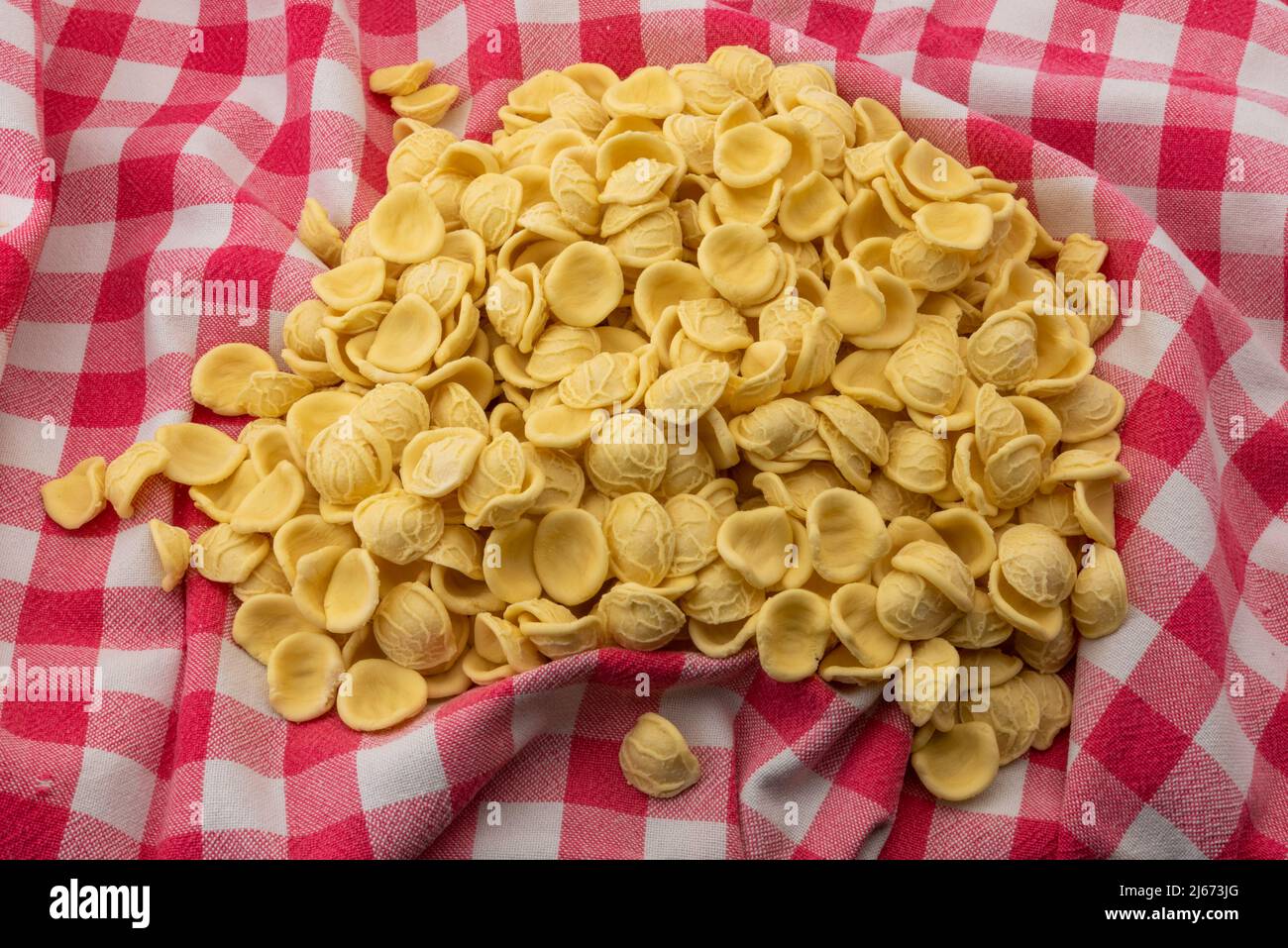 Orecchiette sur nappe à carreaux rouges, pâtes italiennes de Puglia à base de farine de blé dur et d'eau, typiques de la cuisine des Pouilles Banque D'Images