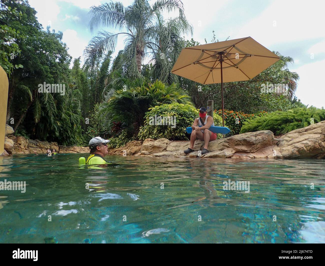 Orlando, FL USA - 21 mai 2021 : les gens flottent sur la piscine de la rivière lente et l'aménagement paysager du parc Discovery Cove à Orlando, en Floride. Banque D'Images