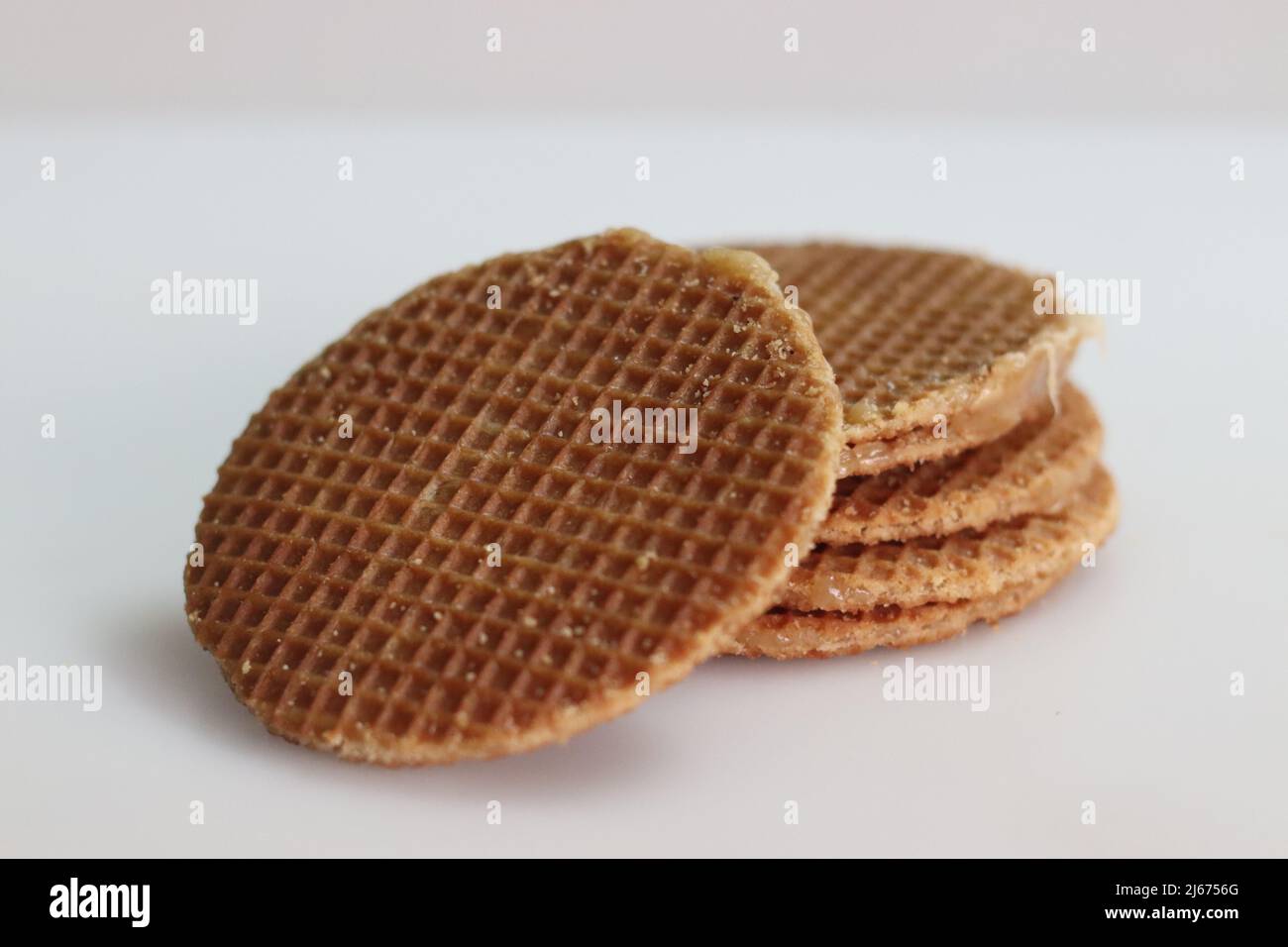 Stoopwafles. Une pile de gaufres à base de sirop jumbo populaires avec du miel. Prise de vue sur fond blanc Banque D'Images