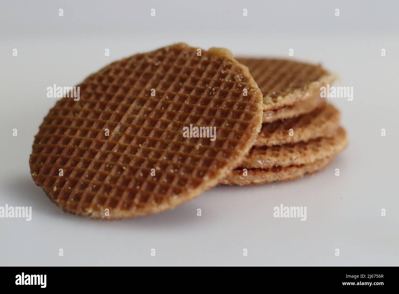 Stoopwafles. Une pile de gaufres à base de sirop jumbo populaires avec du miel. Prise de vue sur fond blanc Banque D'Images