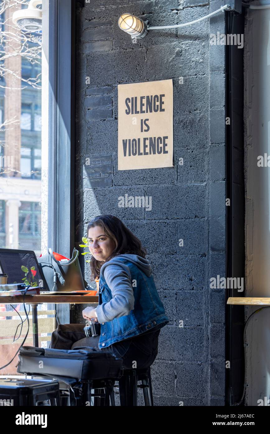 Fille dans dessert Oasis Coffee Roasters avec le signe 'Silence is violence', 1220 Griswold St, Detroit, Michigan 48226, Etats-Unis Banque D'Images
