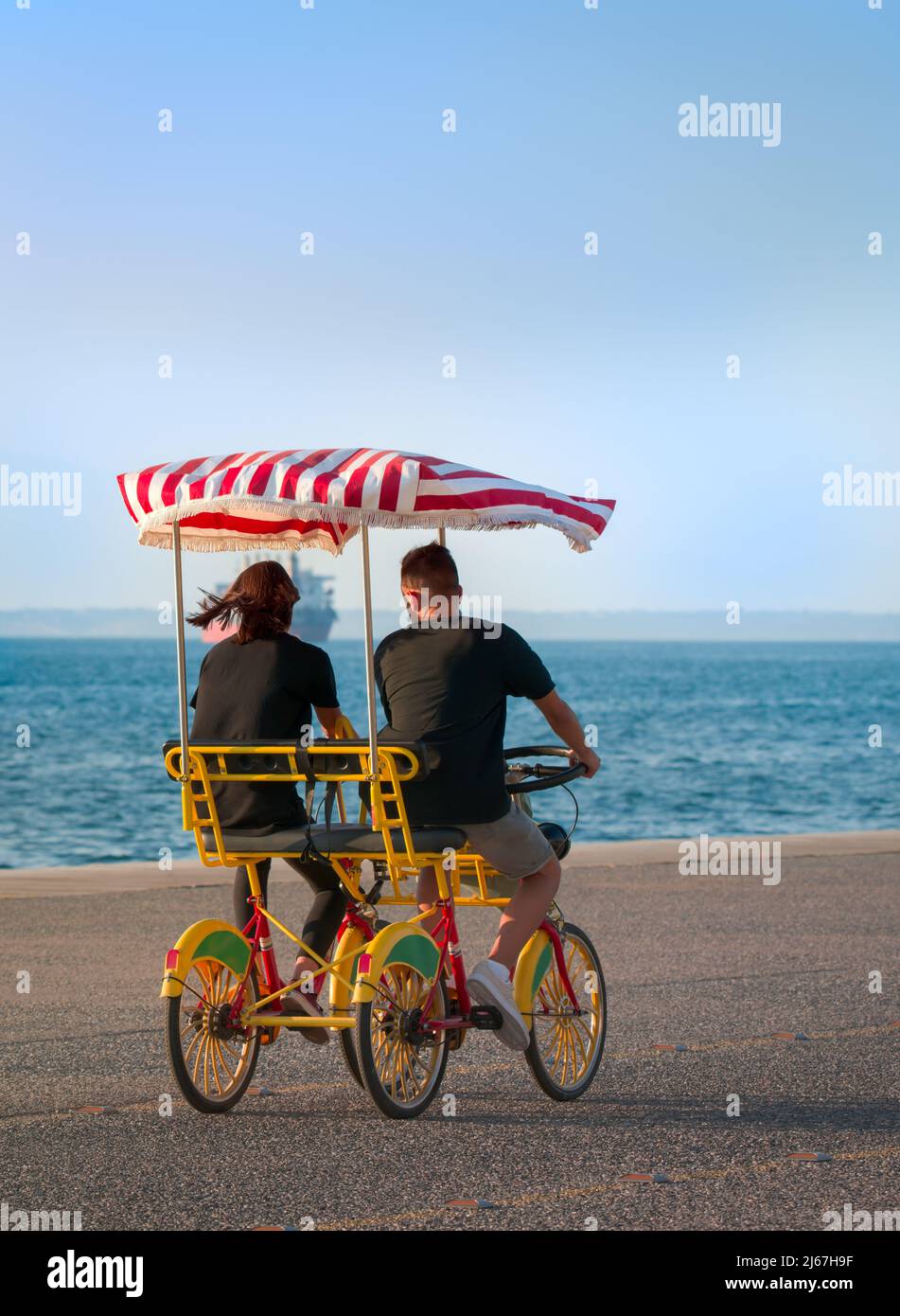 Un jeune couple à vélo à quatre roues (Motor surrey) à la promenade près de la mer photo verticale. Banque D'Images