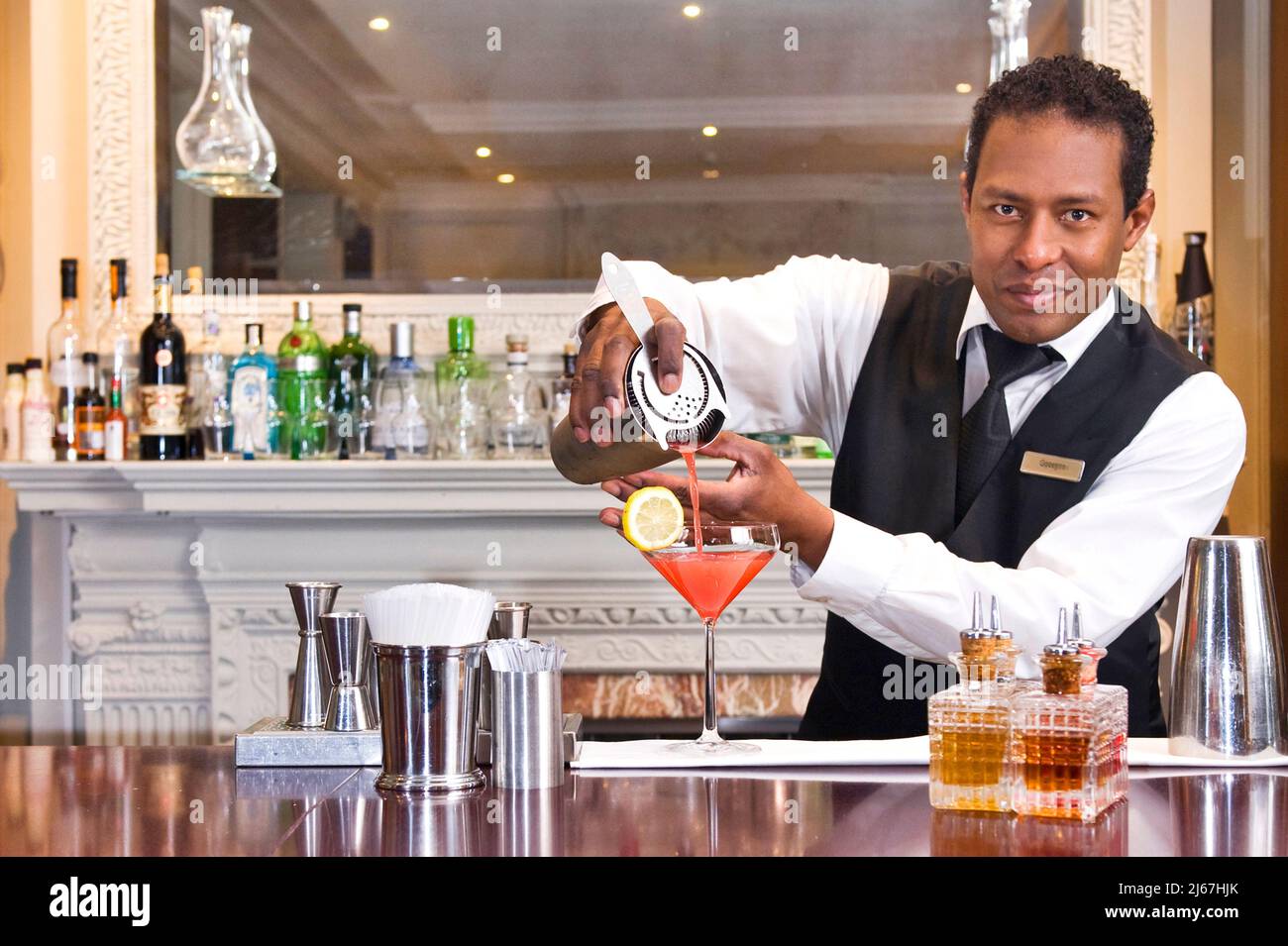 Le barman verse une boisson au comptoir du bar d'un hôtel de luxe Banque D'Images