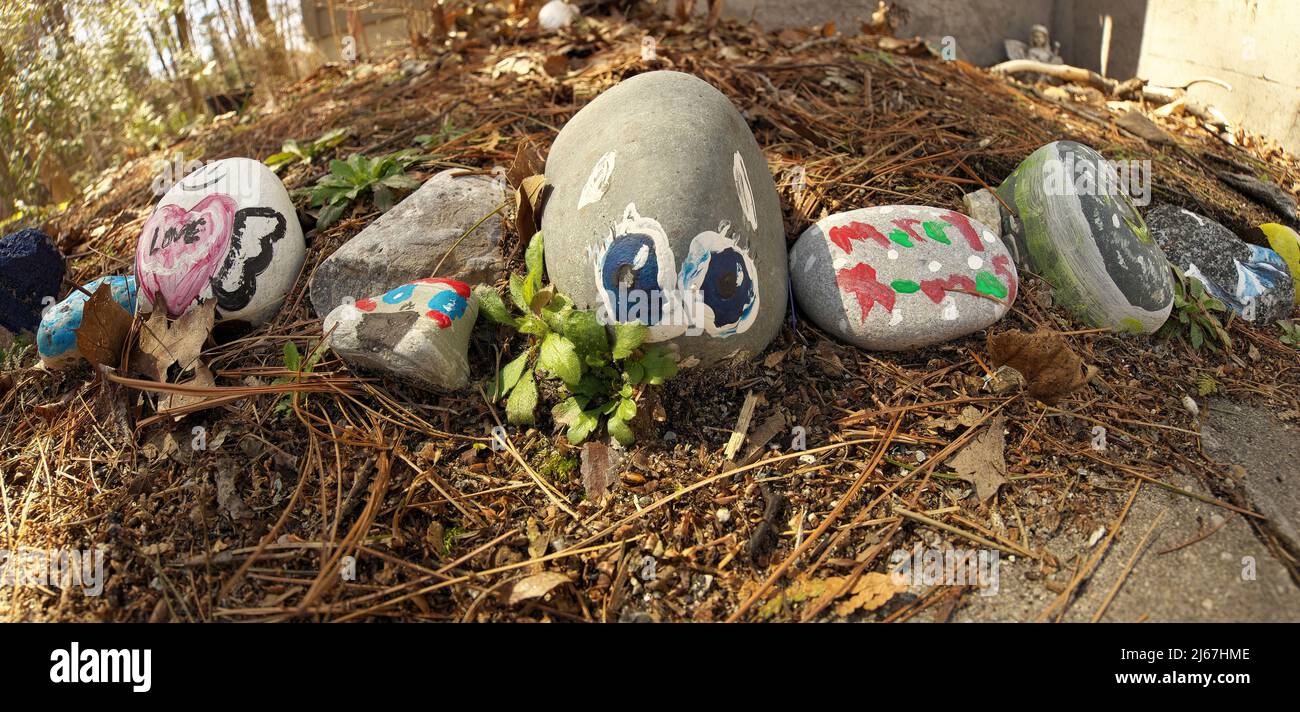 Gros plan sur des pierres peintes de fantaisie colorées dans le jardin de roche pour enfants, bannière panoramique Banque D'Images