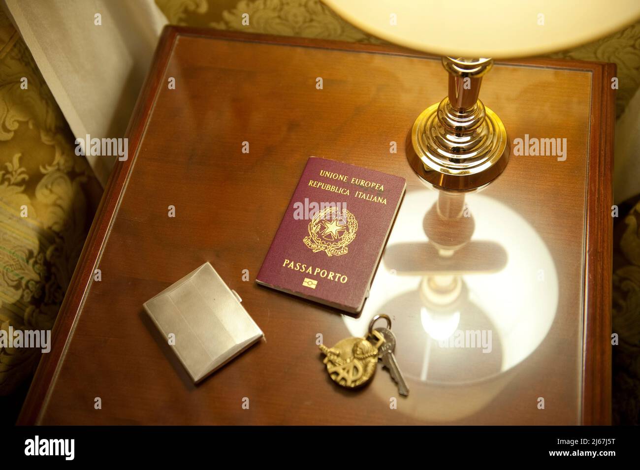 Table de nuit avec passeport, clé d'hôtel et porte-cigarette doré Banque D'Images