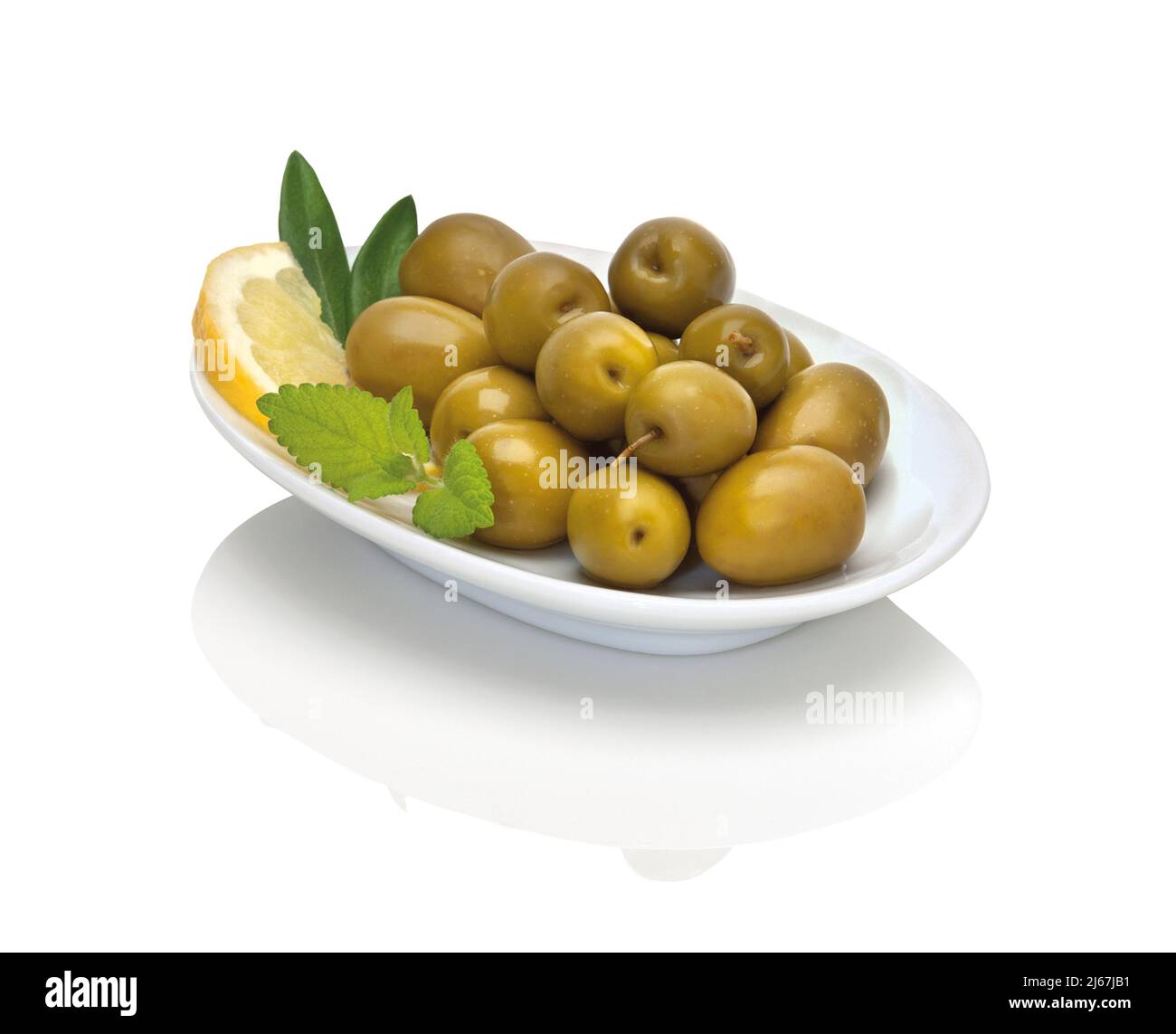olives vertes dans une petite assiette blanche avec une tranche de citron, citronnelle et deux feuilles d'olive sur fond blanc Banque D'Images