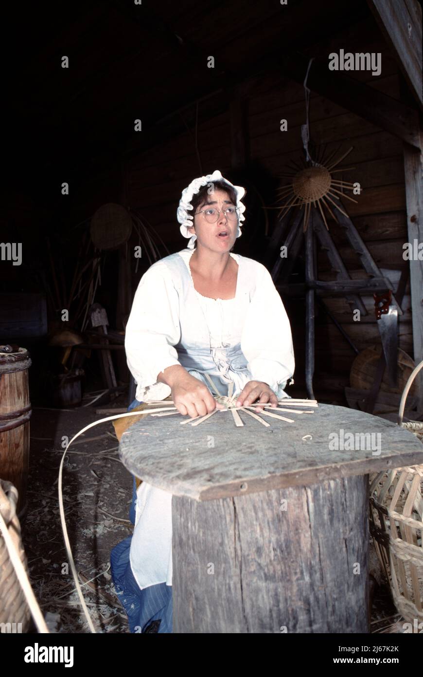 Williamsburg, Virginie. ÉTATS-UNIS 9/1987. Tisserand. Master basket tisserand utilisant des bandes de bois tissées dans un panier de plusieurs tailles pour transporter ou stocker des légumes, des épis de maïs, des fruits, des oeufs, des instruments de couture, bois de chauffage de cuisine, bois de chauffage de cheminée et chiffons à linge. Le tissage du panier est vieux de 1000s ans. Banque D'Images