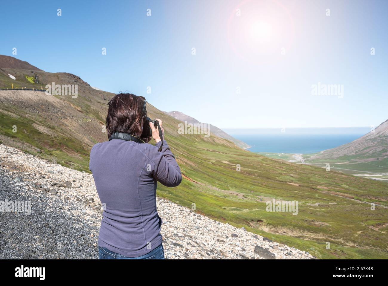 Femme photographe prenant des phots d'une vallée d'une route de col de montagne lors d'une journée ensoleillée d'été Banque D'Images