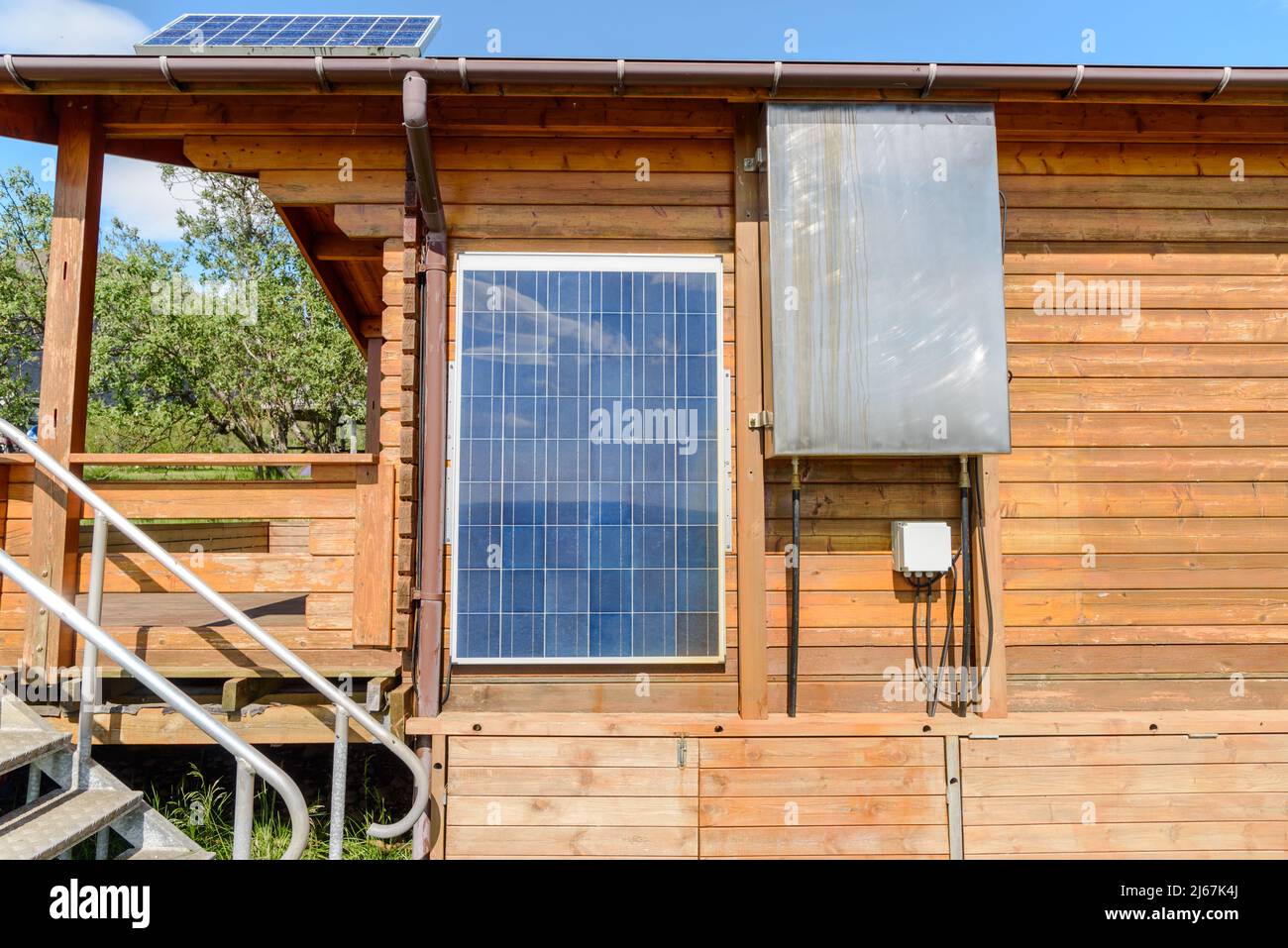 Panneaux solaires sur le mur extérieur et sur le toit d'une cabine en bois par une belle journée d'été. Concept d'énergie renouvelable. Banque D'Images