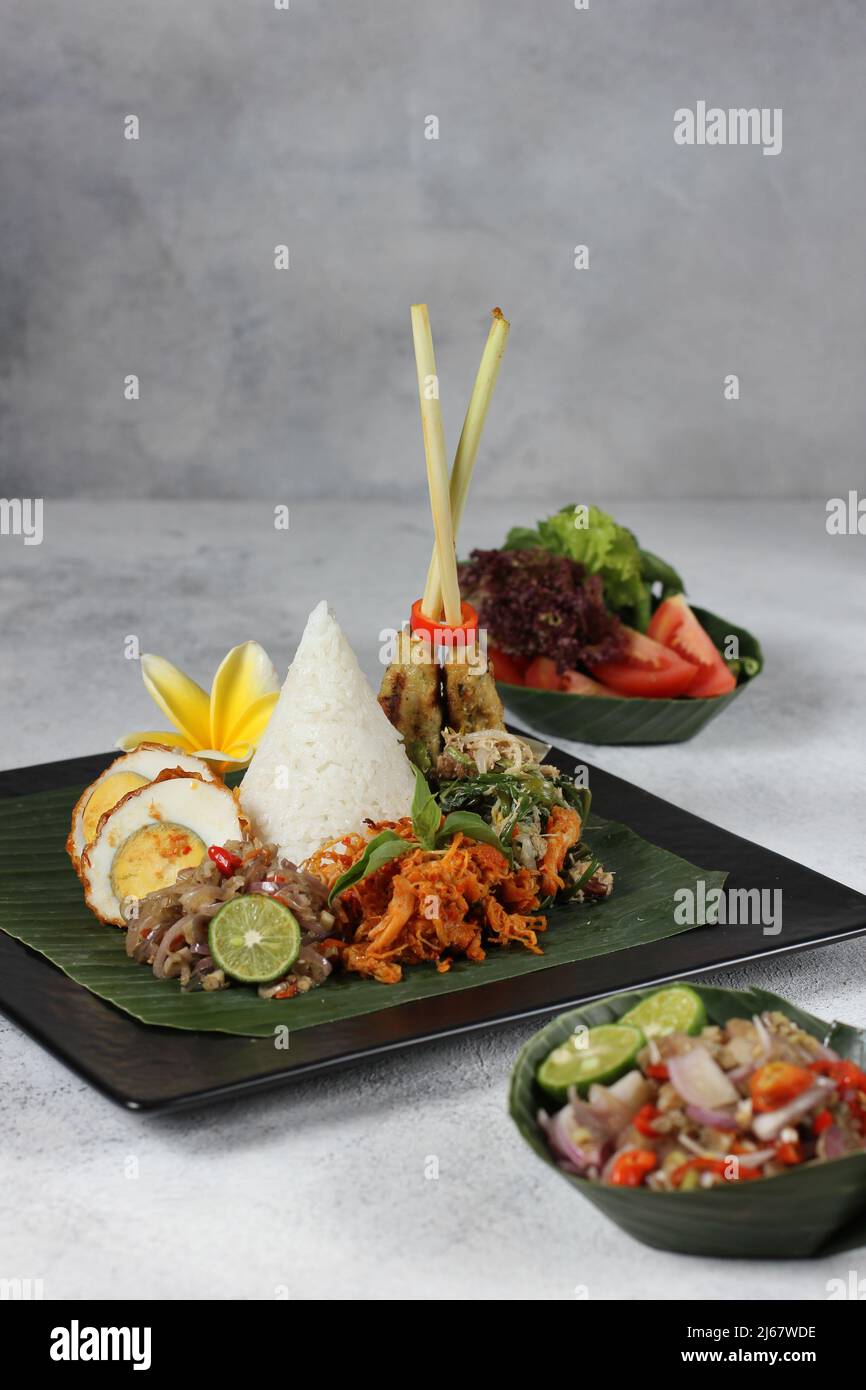 Délicieux nasi bali épicé avec œuf de Chili, satay de poulet et salade végétagie sur fond blanc plat noir Banque D'Images