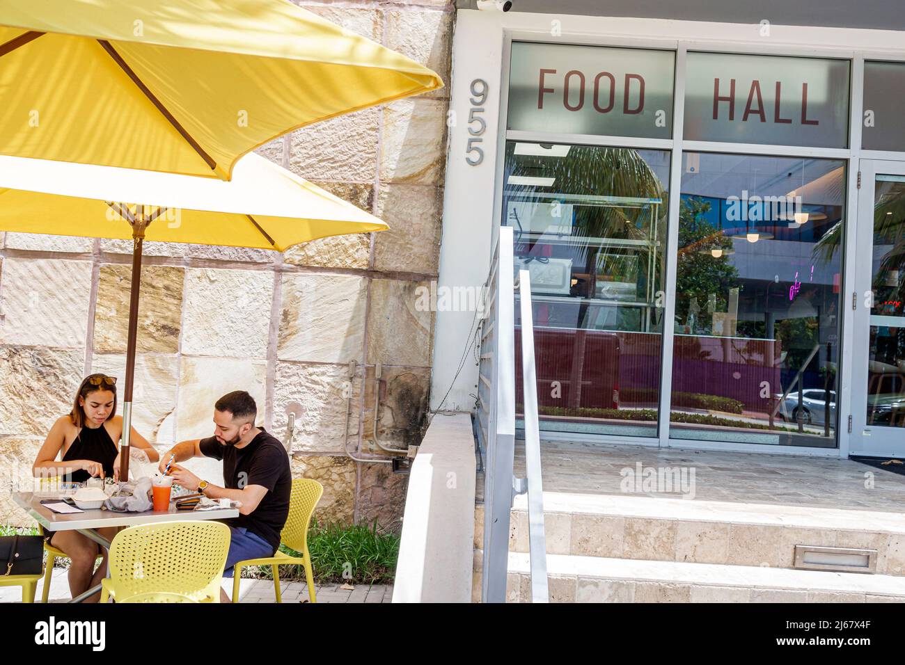 Miami Beach Florida Alton Food Hall & Eatery extérieur couple homme femme dîner table jaune parasols restaurant Banque D'Images